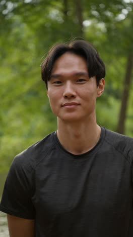 Vertical-Video-Portrait-Of-Smiling-Mid-Adult-Man-Exercising-Doing-Work-Out-Outdoors-In-Forest-Wearing-Sports-Clothing-Shot-In-Real-Time